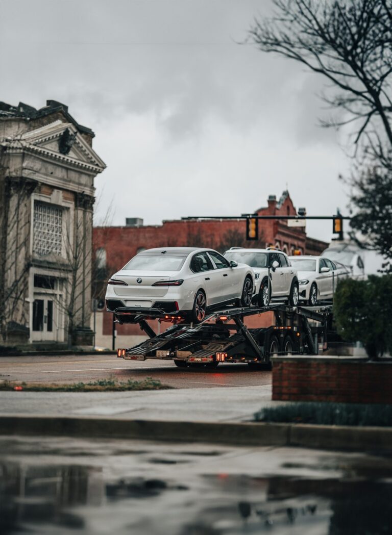 A truck driver and a dispatcher discussing a vehicle transport schedule next to a car hauler.